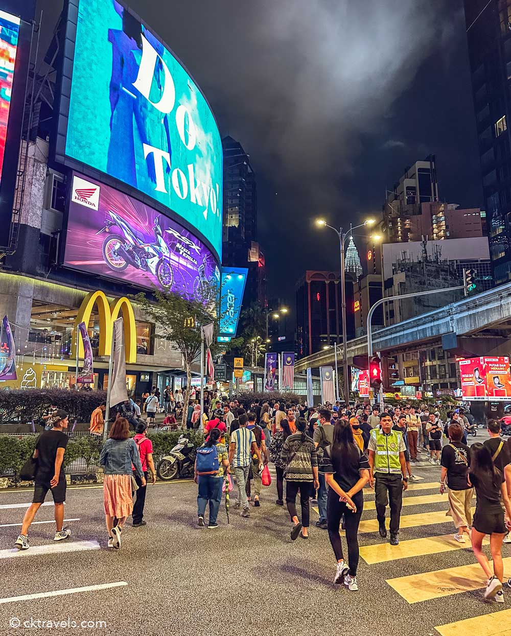 Bukit Bintang Crossing at night with pedestrians, monorail and illuminated city billboards